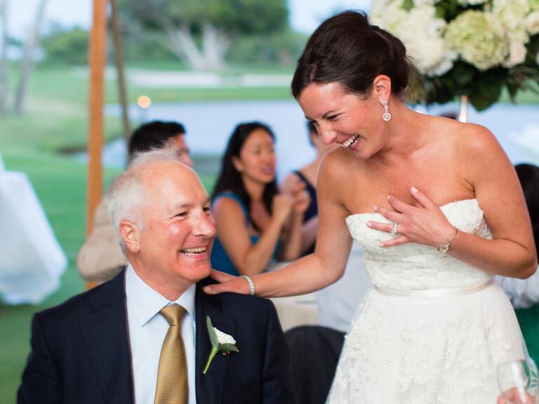 A bride laughs with her father at her wedding reception