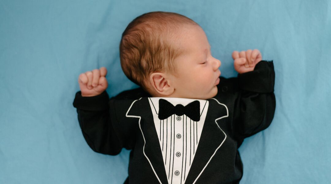 Baby sleeping in tuxedo outfit
