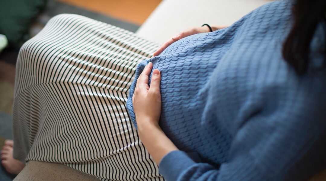 pregnant woman hands on belly indoors