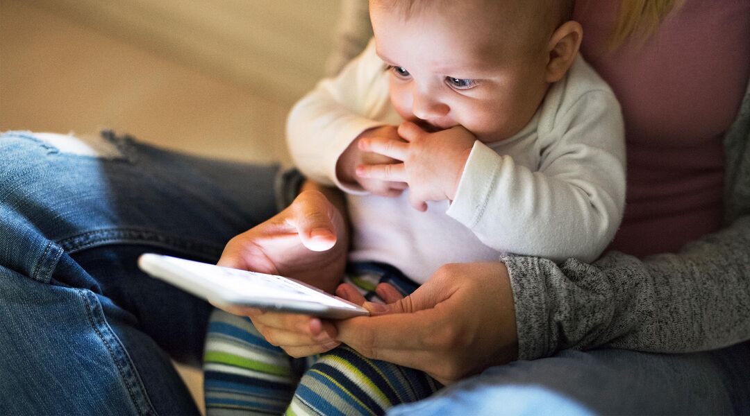 Baby watching as mom interacts with smart phone
