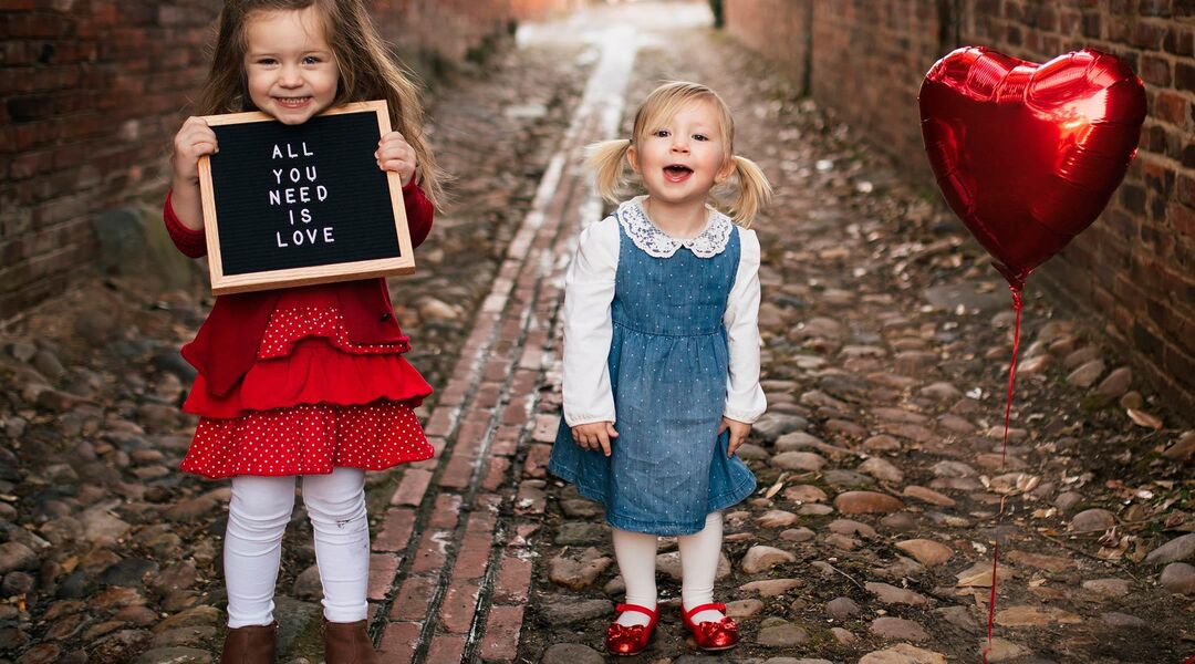 two little girls dressed for valentine's day and holding letterboard