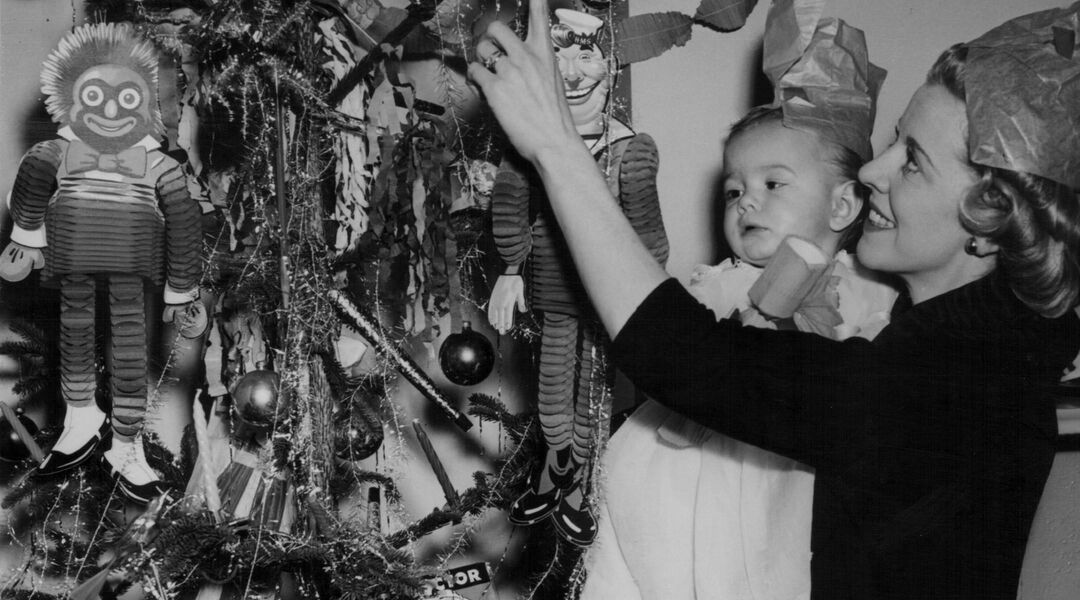 Retro photo of mom holding baby while decorating Christmas tree. 