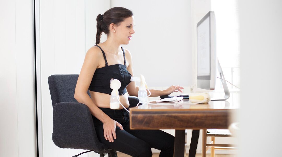 Woman using a hands-free breast pump at her computer