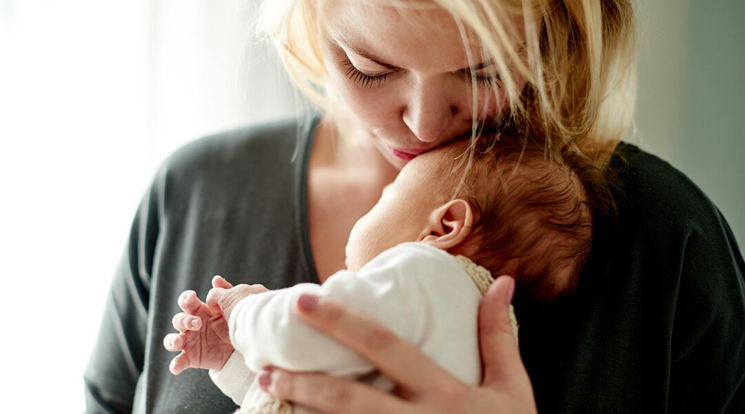 woman cuddling newborn
