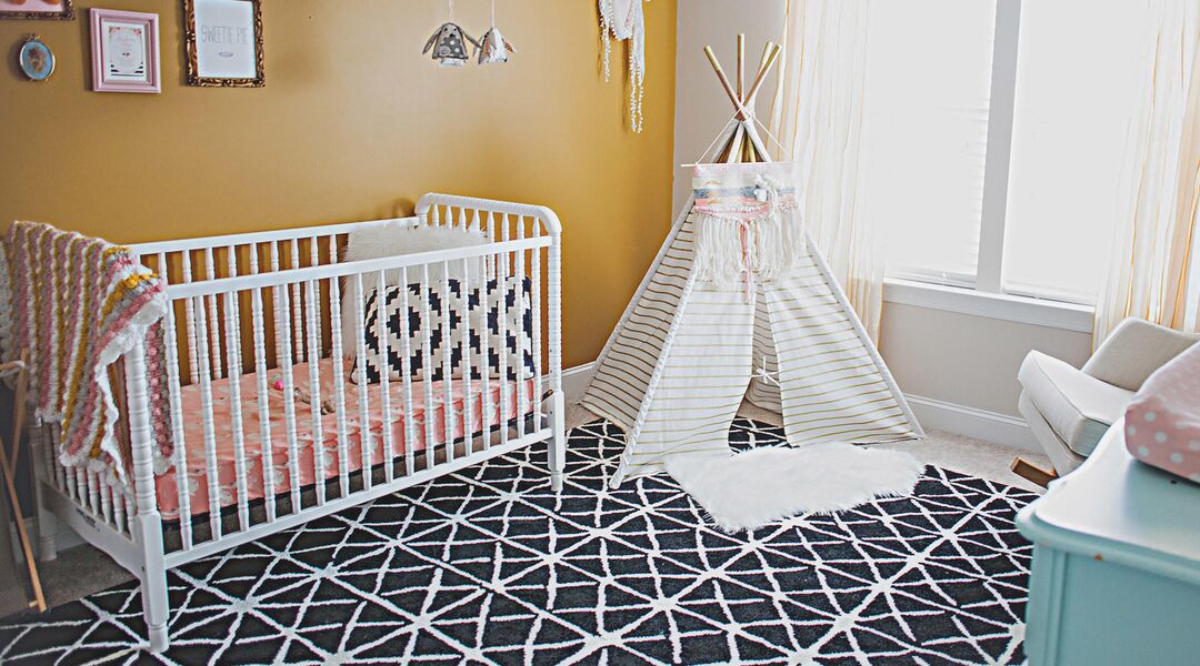 Baby nursery room with white crib and tee-pee. 