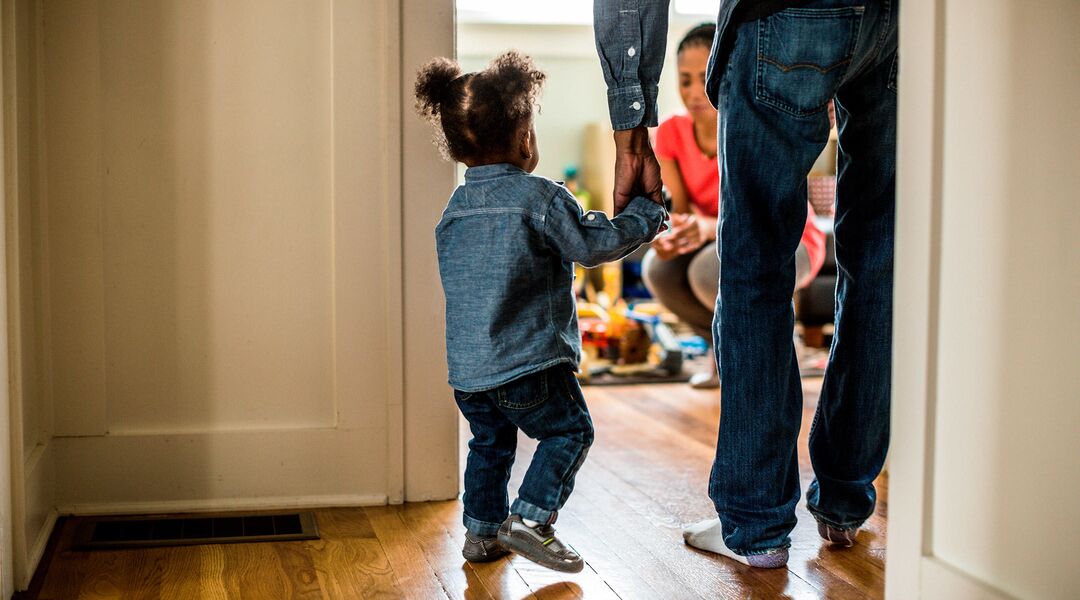 dad holding toddler daughter's hand and walking into room