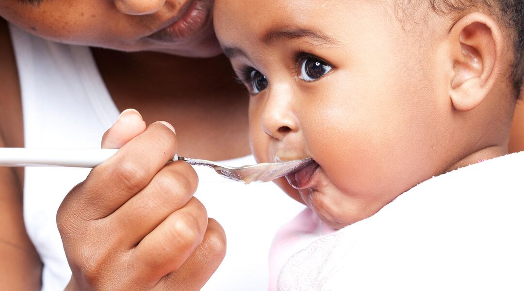 baby being spoon fed by mom