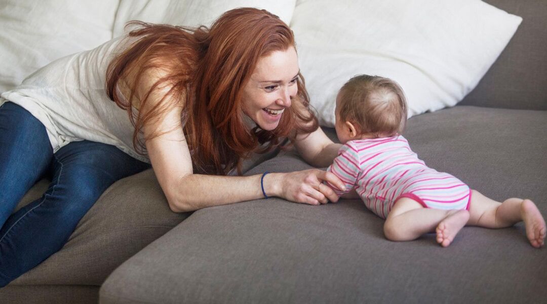 mom playing with infant on couch