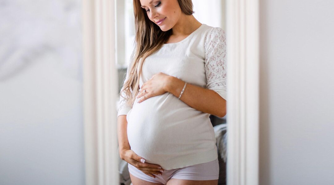 pregnant woman looking in mirror