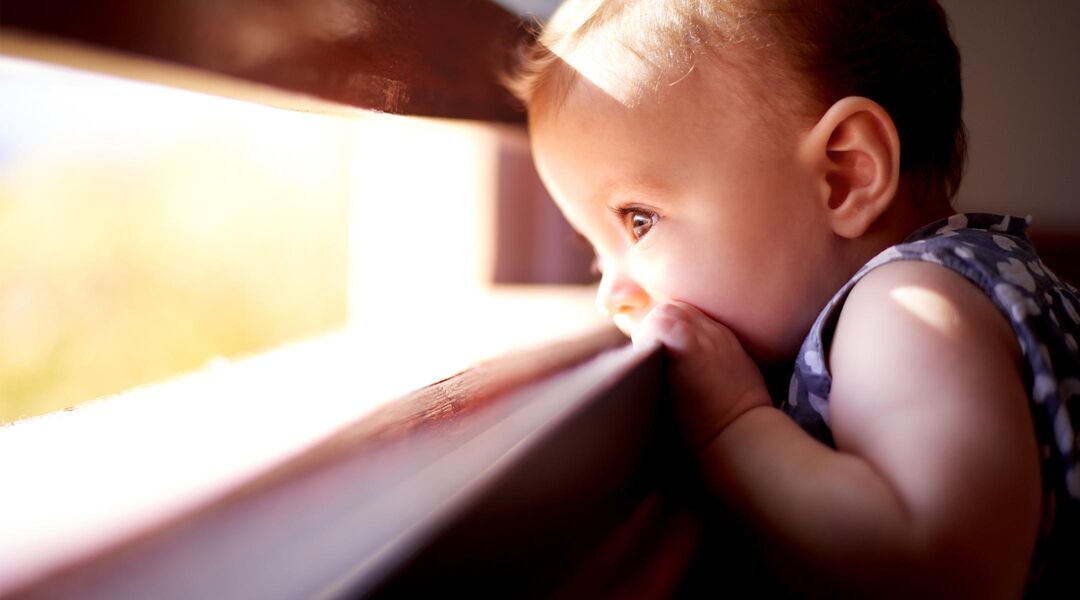 baby chewing on window sill