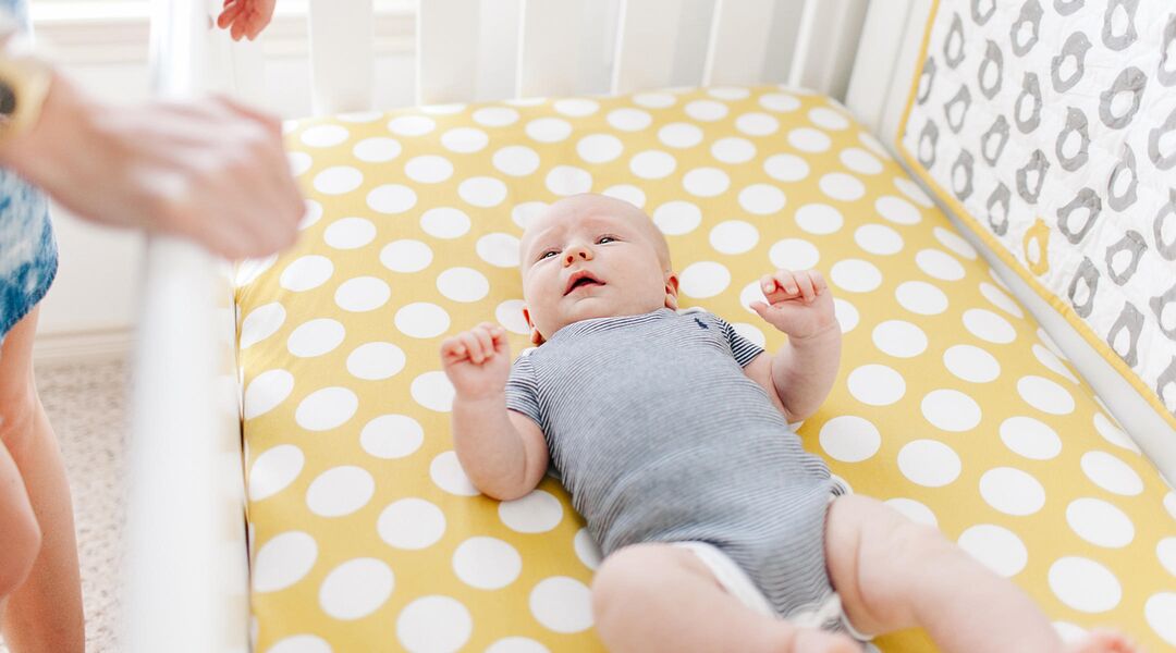 parent putting baby to sleep in crib being mindful of sids