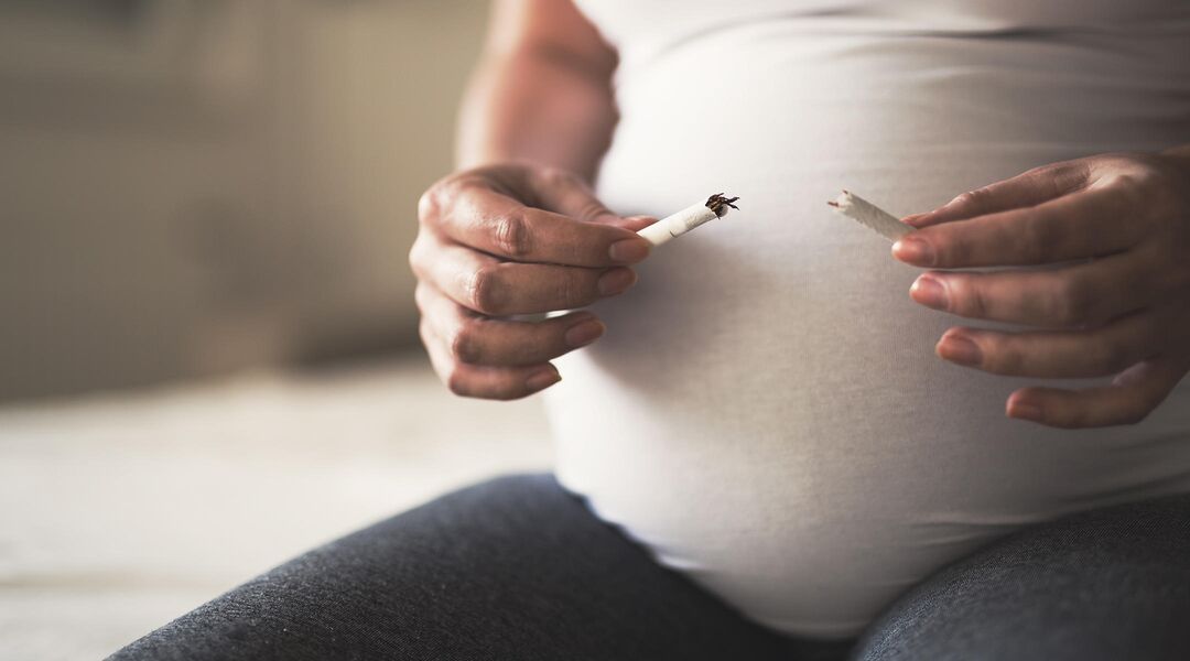 Pregnant woman holding cigarette