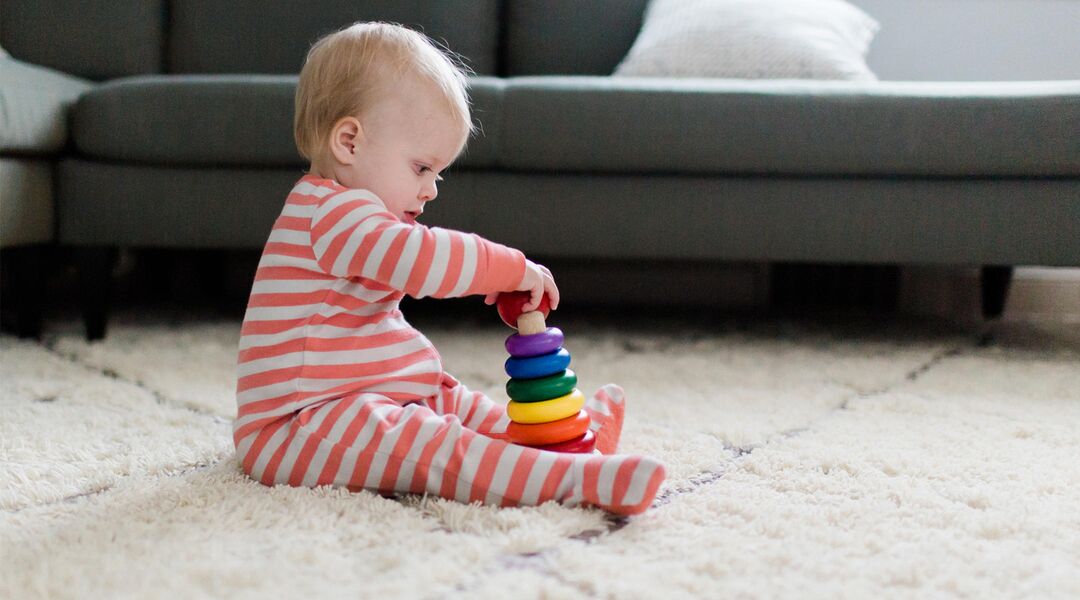 Baby in pajamas playing with ring toy