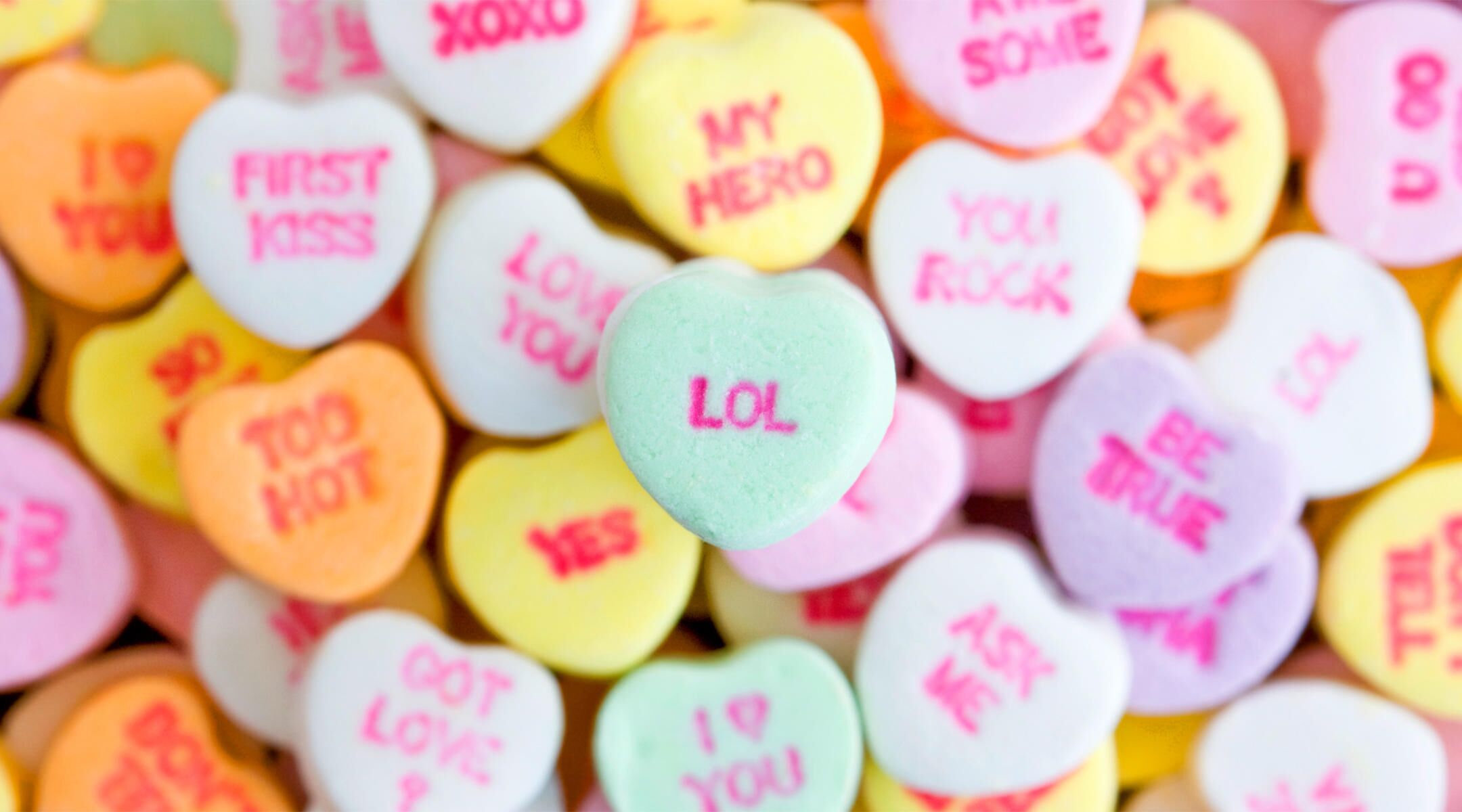 Pile of candy hearts with messaging, center one reading LOL. 