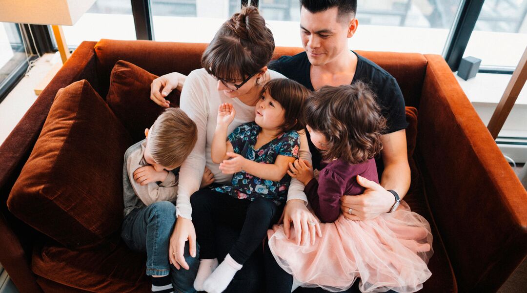 family with three kids hanging out on couch.