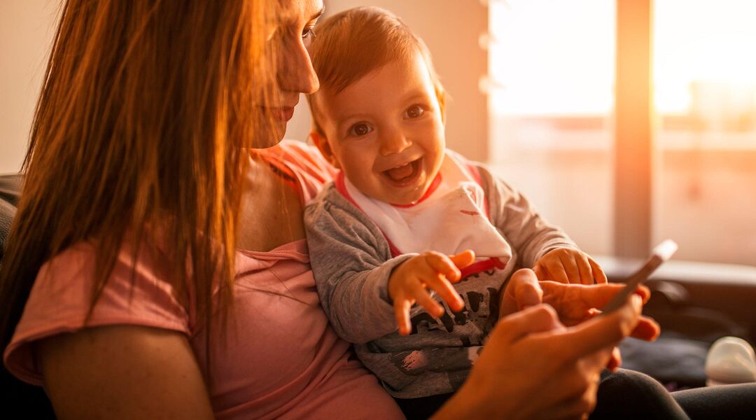 mom and laughing baby watching video on phone