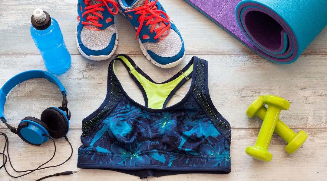 Arrangement of exercise gear, a water bottle, sports bra, shoes and free weights.