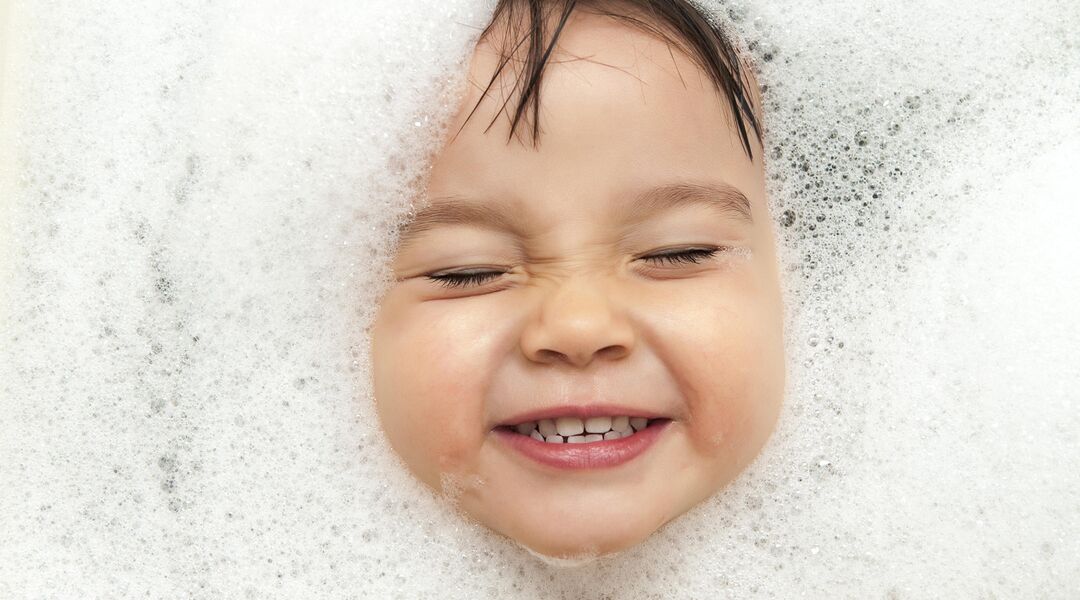 Toddler submerged and playing in the bath.