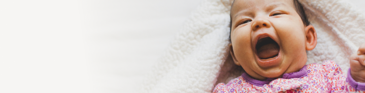 Baby girl laying on bed smiling and laughing