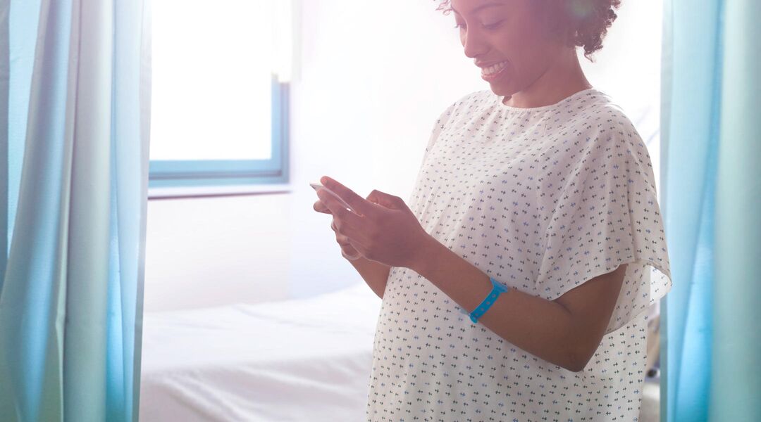 Pregnant woman in hospital delivery room using her cell phone. 