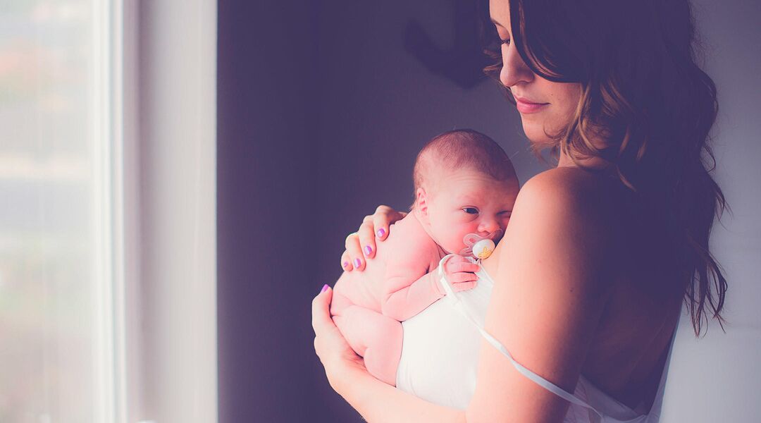 new mom holds newborn baby at home