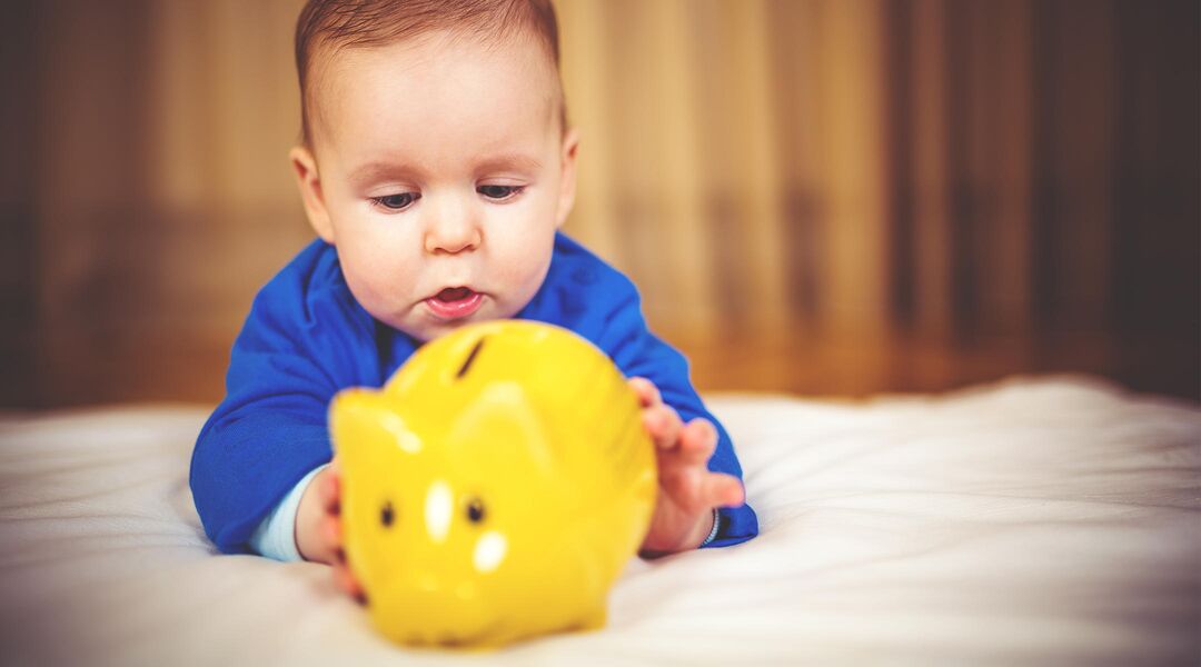 Baby playing with yellow piggy bank