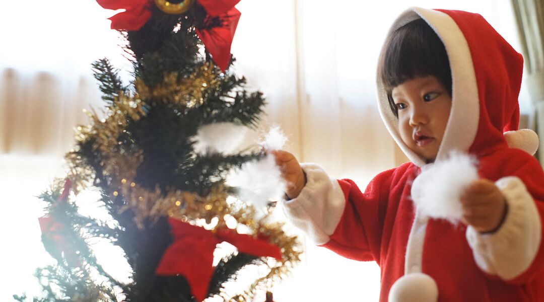 Little girl in santa outfit decorating tree