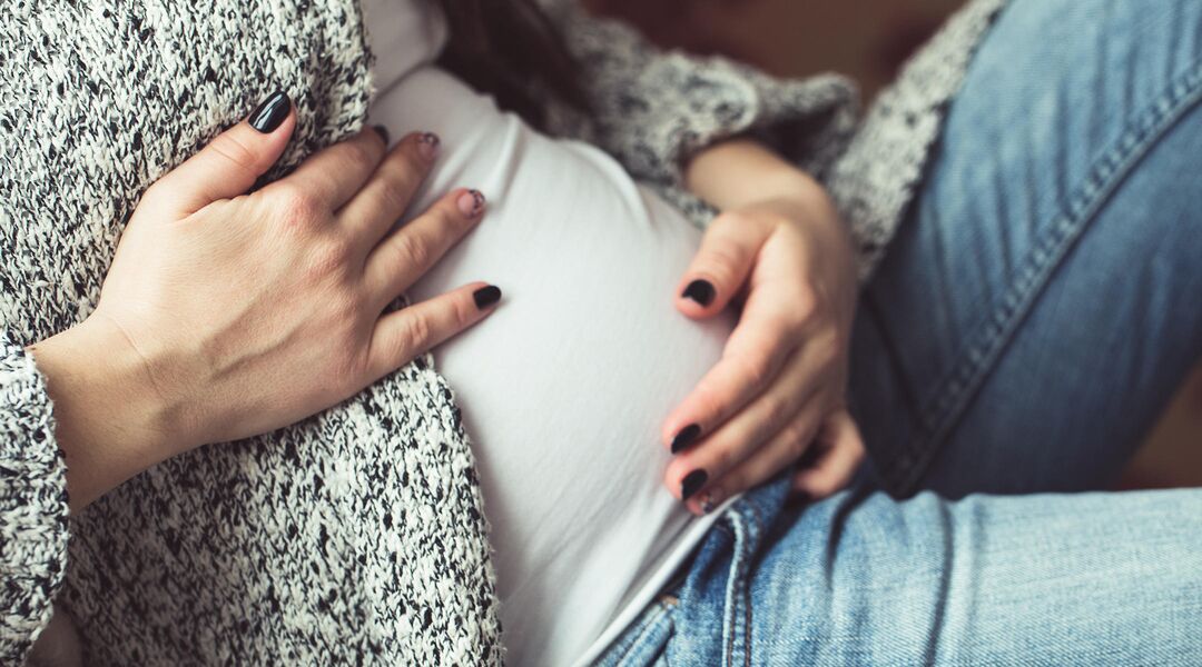 Pregnant woman in jeans touching her belly