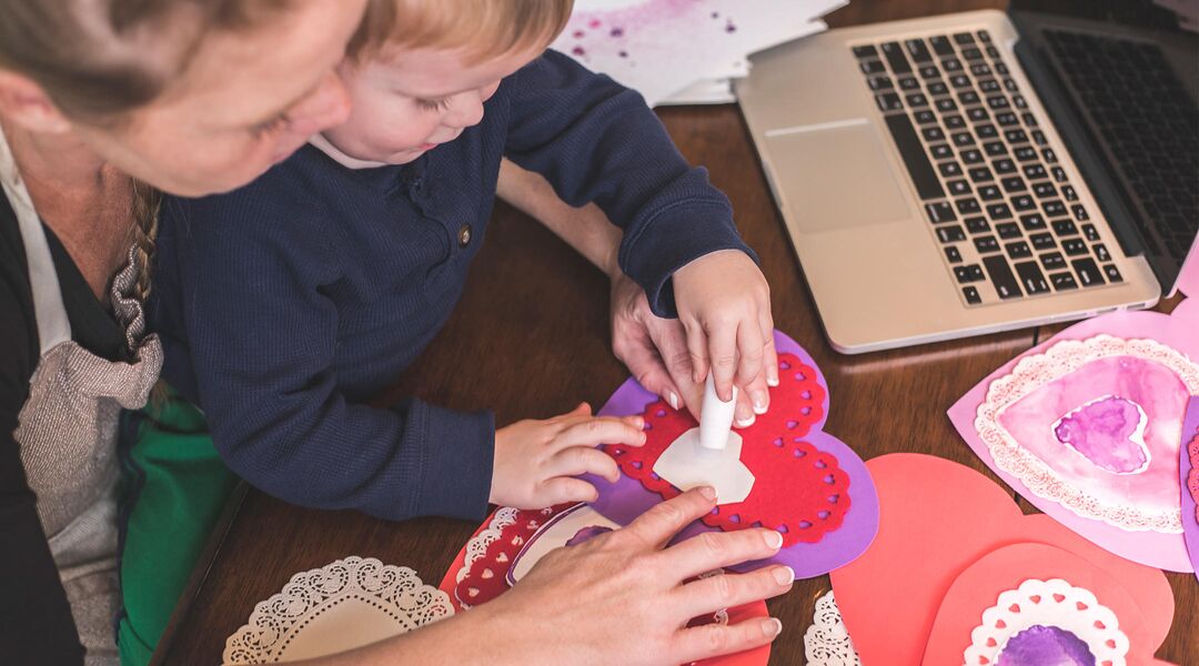 Mom making heart-shaped Valentine's with son in her lap