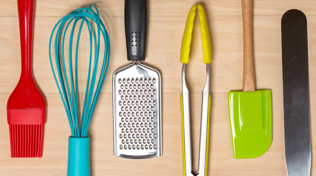 Cooking tools lined up on wooden surface. 