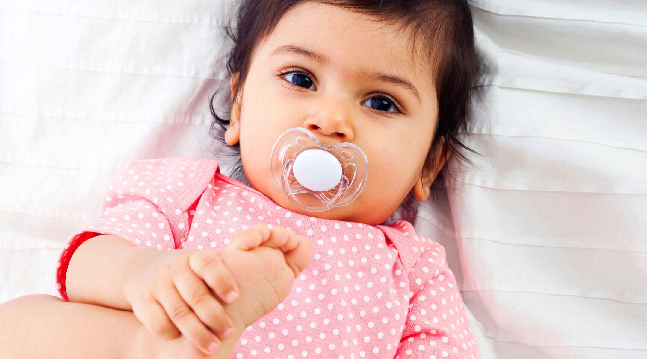 baby laying down with pacifier in mouth