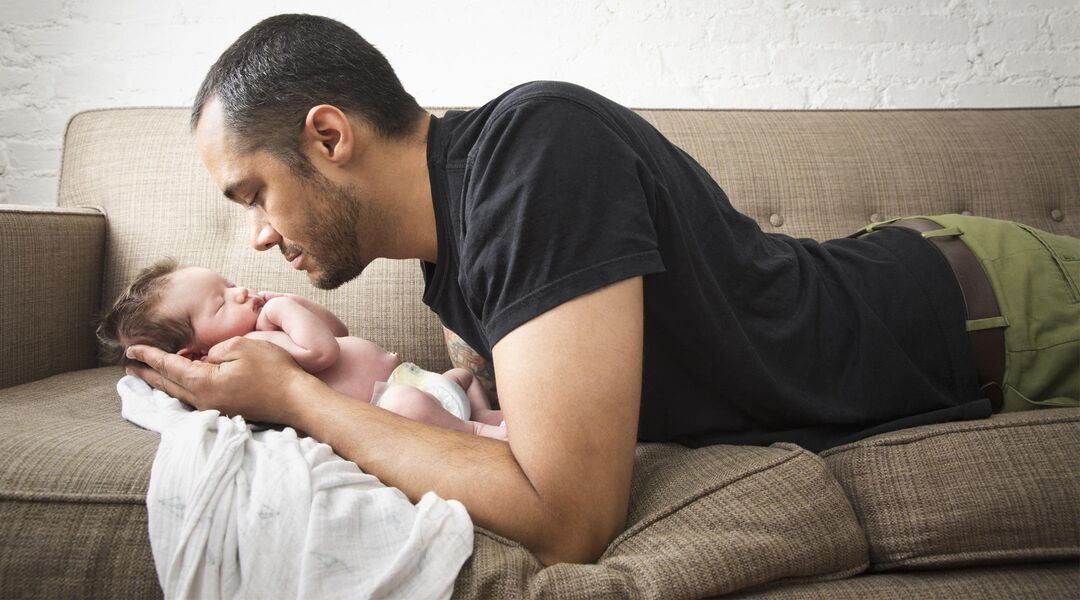 man looking at baby cradled in his hands
