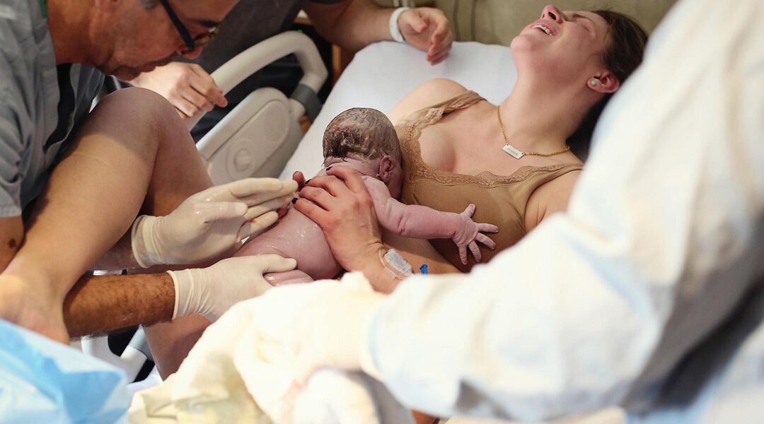 Mother catching baby in delivery room