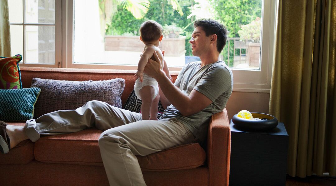 man holding baby on couch