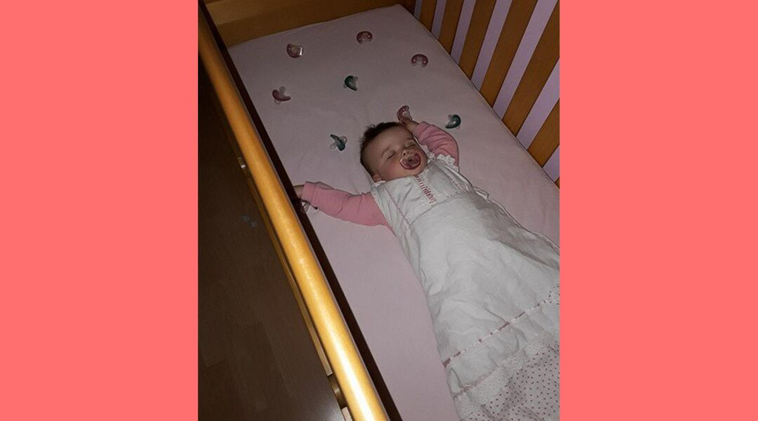 Baby sleeping in crib surrounding by pacifiers