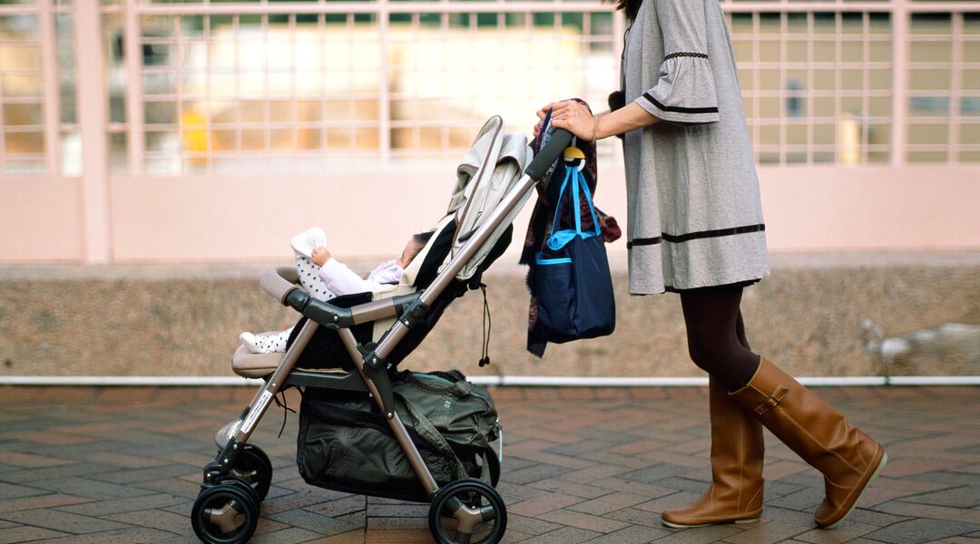 Mom pushing stroller and looking at phone while shopping. 