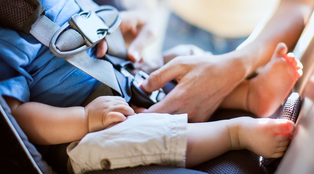 Woman strapping baby into car seat