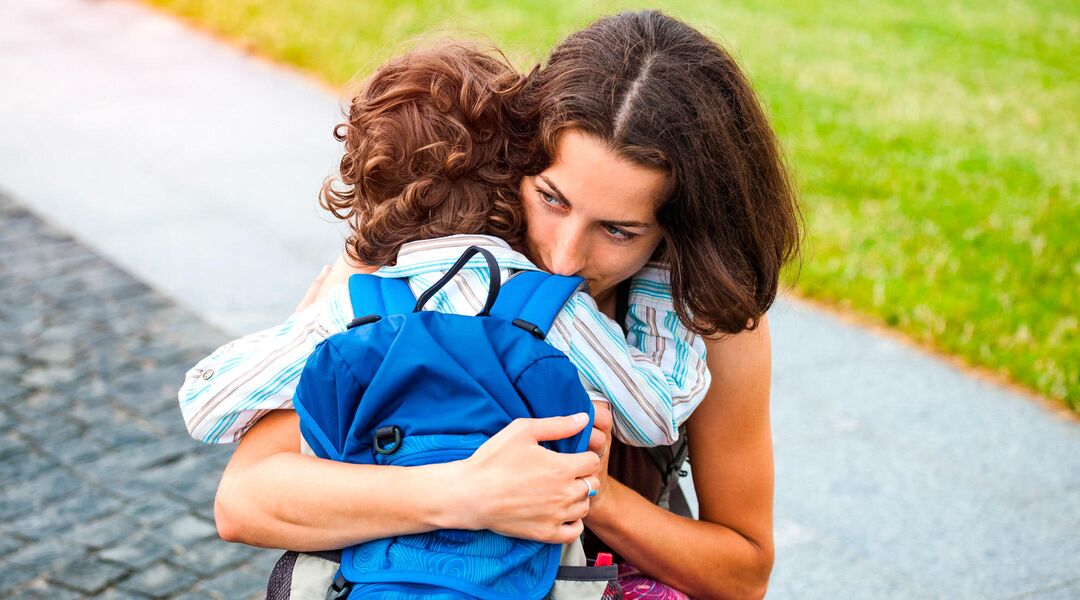 woman hugging a toddler with a backpack