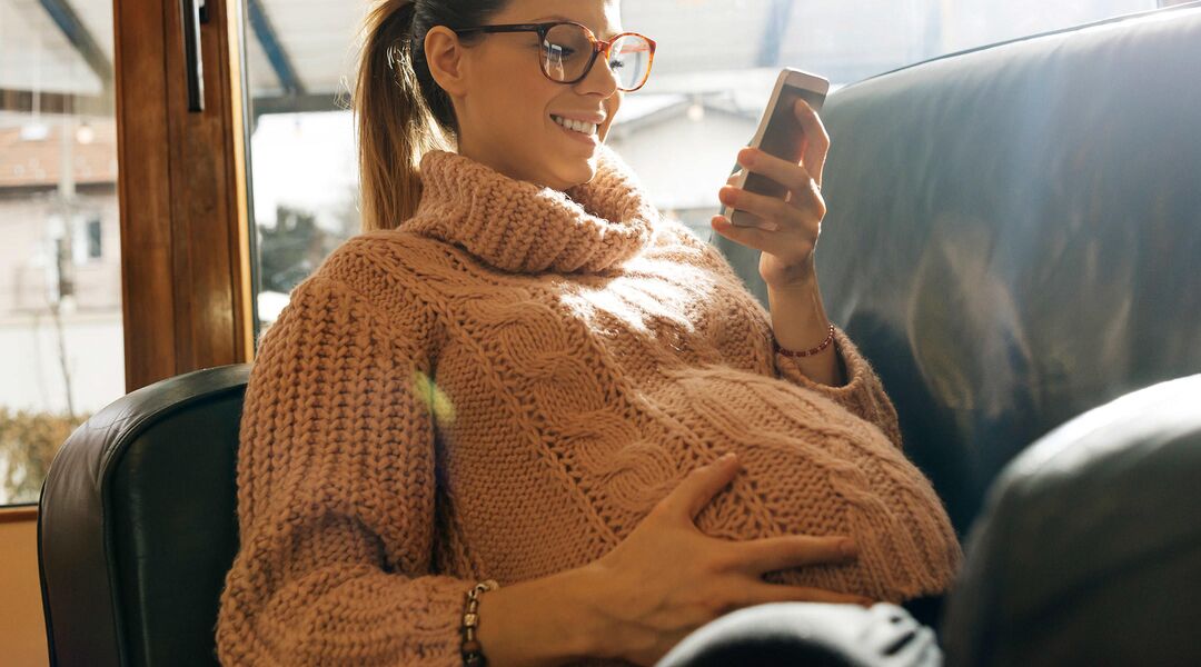 pregnant woman smiling and looking at her phone