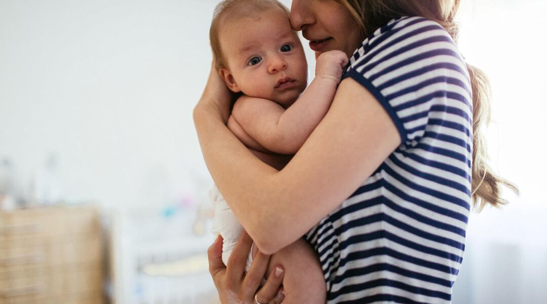 woman holding a baby close to her chest