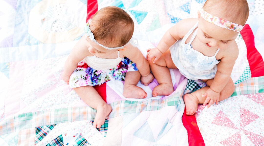 twins playing outside on blanket